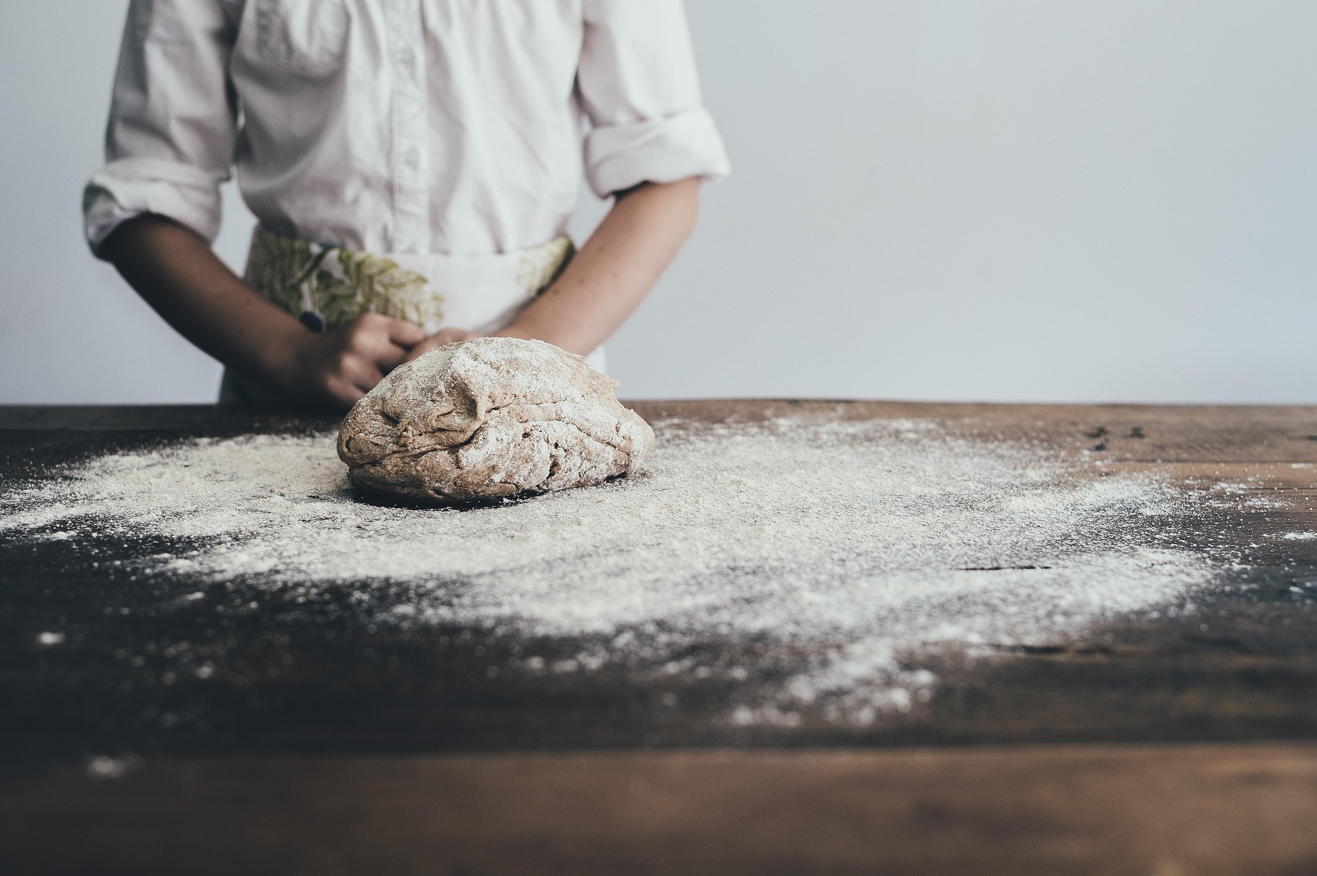 Hands kneading dough on a wooden table — small dreams count too.