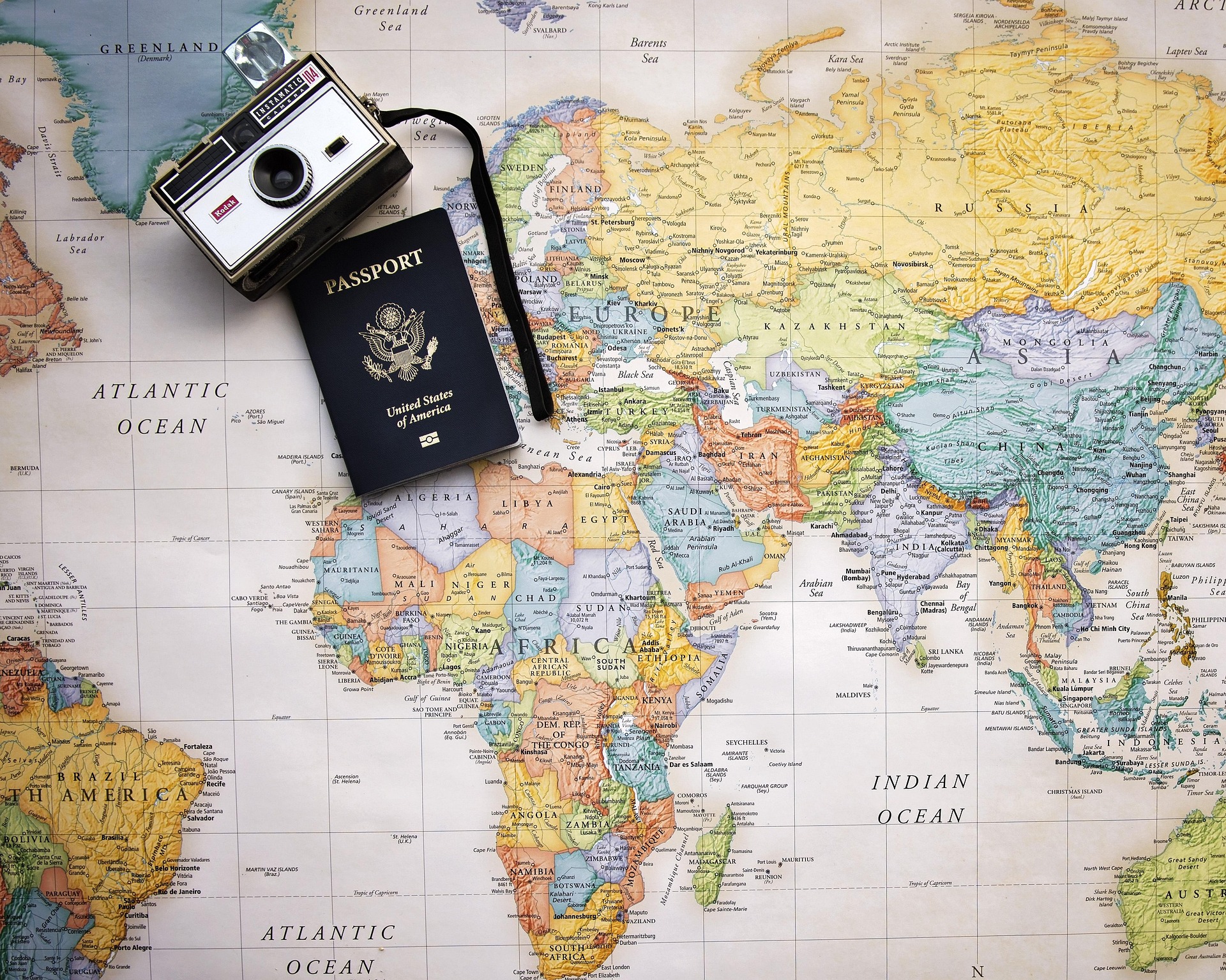 A world map with a passport and vintage camera — plan the trips, then shade the countries.