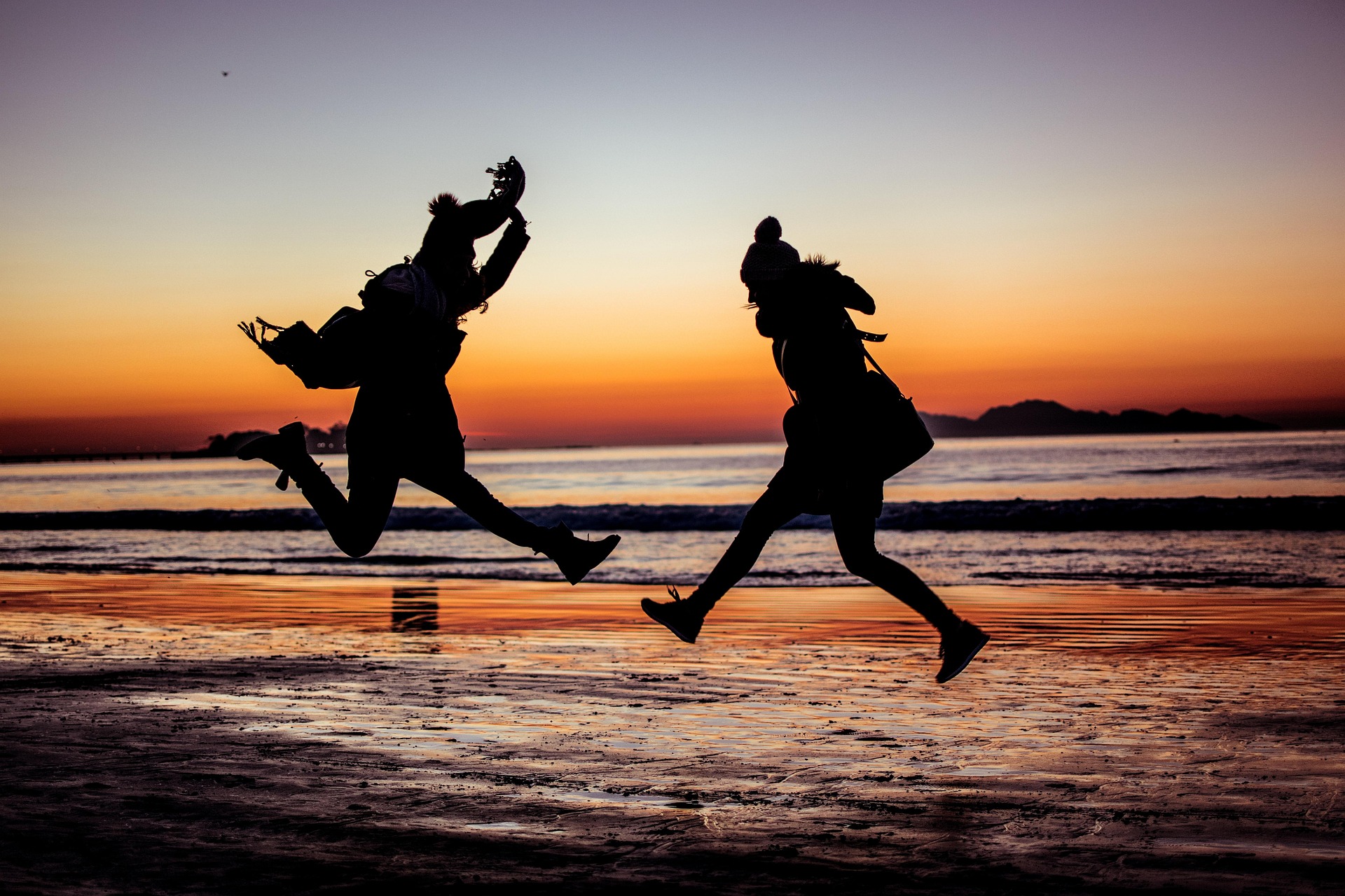 Two people jumping on a beach at sunset — the kind of shared moment a couples bucket list is built from.